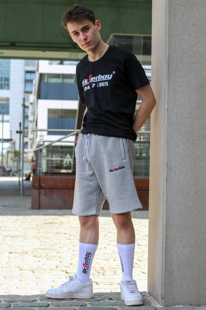 junger typ trägt grauen sk8erboy trainingsanzug in lang mit passender hose und 365 t-shirt zu seinen weißen nike sneaks und crew socks