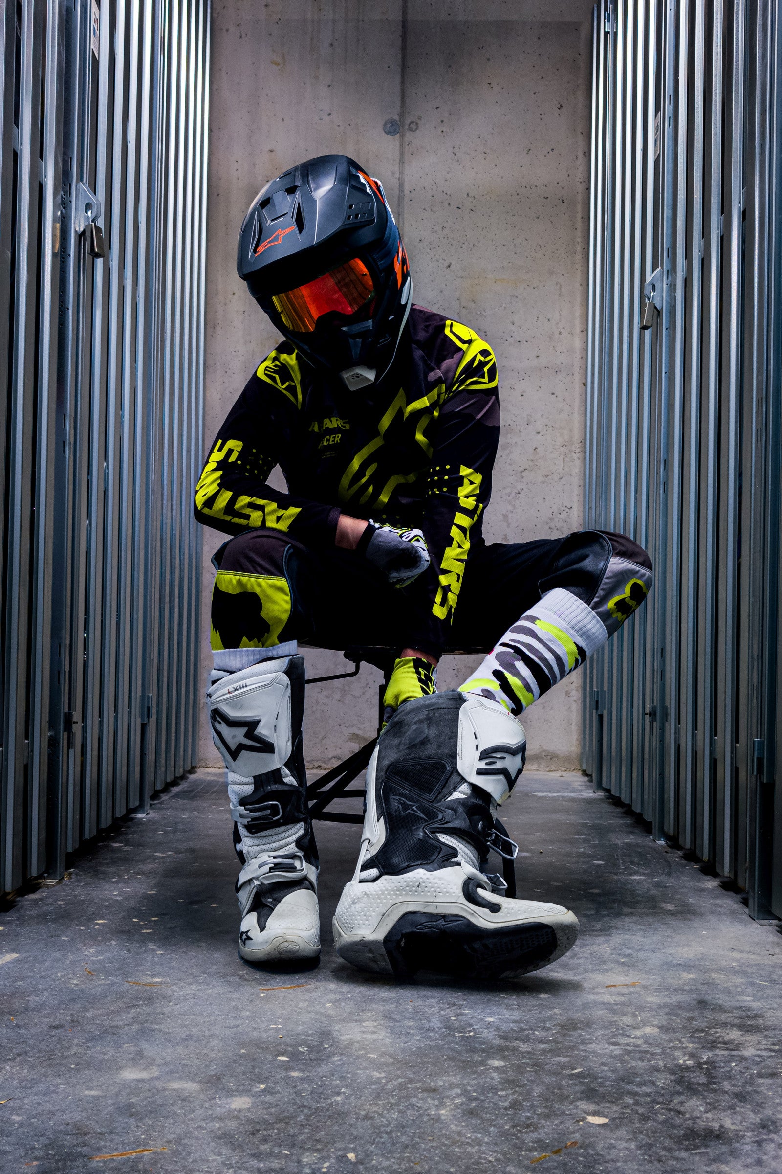 motocross biker in neon gelben dress mit cross boots und mx socks in neon gelb von sk8erboy von vorne in den boots sitzend